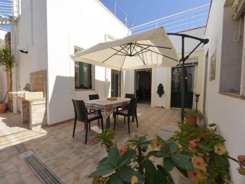 un patio con una mesa y una sombrilla blanca en Villa Giardino delle Meraviglie by Interhome, en Floridia