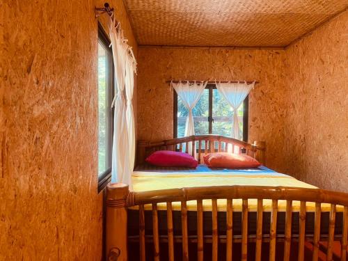 a bedroom with a bed with two pillows and a window at Dawdoylisu Chiangmai in Ban Ton Kham