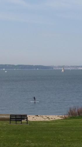 a person on a surfboard in the water near a bench at The Waters Edge in Lee-on-the-Solent