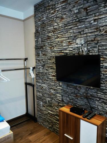 a living room with a stone wall with a flat screen tv at Erika Vendégház in Mogyoród