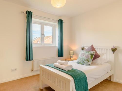 een slaapkamer met een bed met groene gordijnen en een raam bij 4 Bed in Beadnell 79217 in Beadnell
