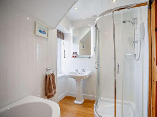 a white bathroom with a shower and a sink at 3 Bed in Craster 79436 in Craster