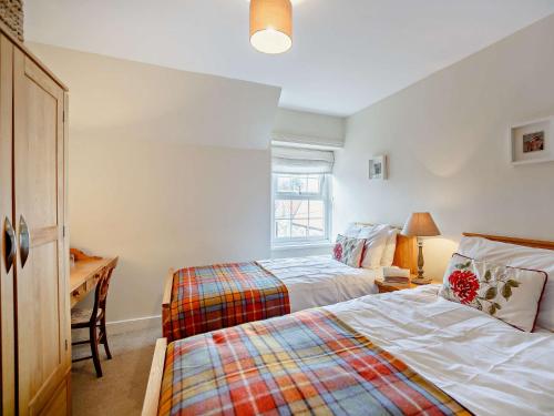 a bedroom with two beds and a desk and a window at 3 Bed in Craster 79436 in Craster