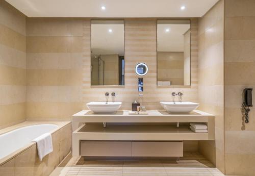 a bathroom with two sinks and a bath tub at HomesGetaway- Lovely 1BR in Hyatt Regency Creek Heights Residences in Dubai