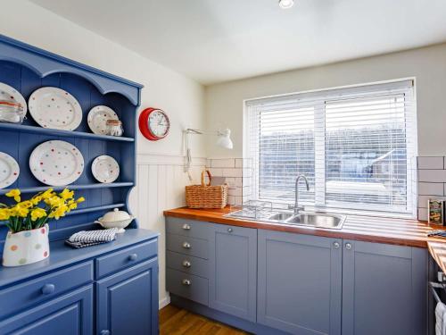 a blue kitchen with a sink and a window at 2 Bed in Berwick-upon-Tweed 82189 in Spittal