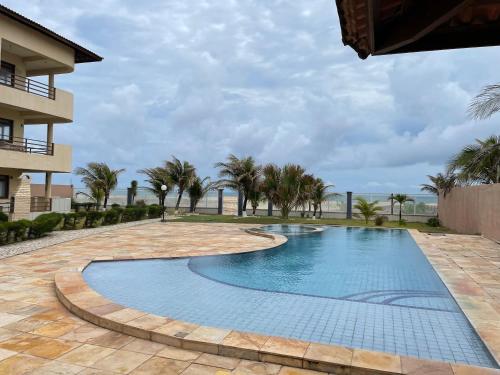 a swimming pool in a resort with palm trees at Apartamento de Frente para o Mar na praia da Taiba Ceará in Taíba