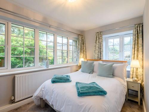 um quarto com uma grande cama branca e janelas em 3 Bed in Corfe Castle 81369 em Corfe Castle
