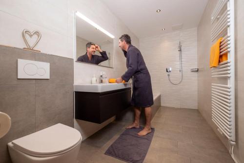 a man standing in a bathroom looking in the mirror at Apart Stiegler in Stumm