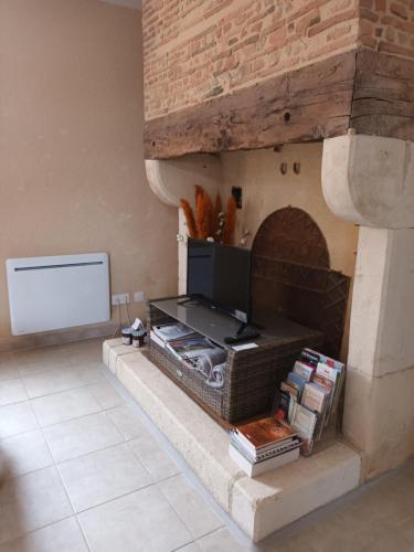 a living room with a stone fireplace with a tv at GÎTE AUX BOIS D'EN TEMPS in Lunas