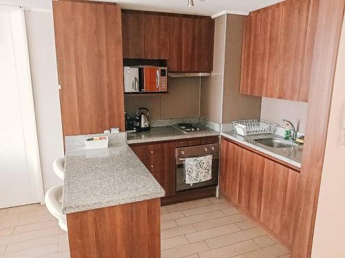 a small kitchen with wooden cabinets and a counter top at Departamento en Calama in Calama