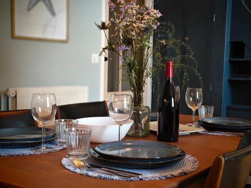 un tavolo in legno con una bottiglia di vino e bicchieri di Les Hauts de Morlaix a Morlaix