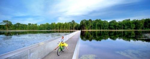 a person riding a bike on a bridge over a lake at Chalet Relax in Zutendaal