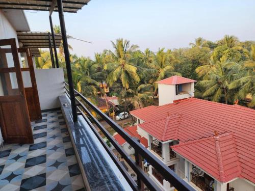 a balcony of a house with a red roof and palm trees at Coastal Suites Apart Hotel ---- 8 minutes walk to beach in Benaulim