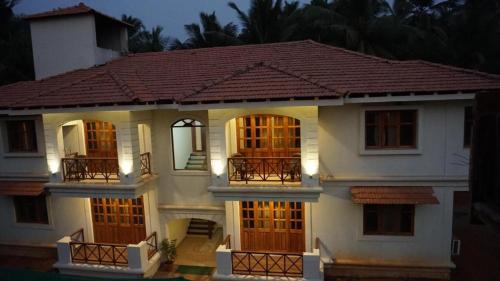 a large white house with wooden doors and windows at Coastal Suites Apart Hotel ---- 8 minutes walk to beach in Benaulim