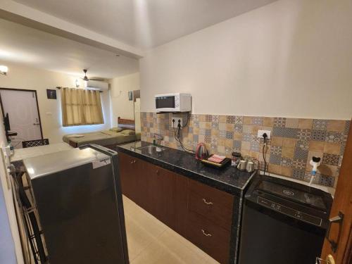 a kitchen with a black refrigerator and a microwave at Coastal Suites Apart Hotel ---- 8 minutes walk to beach in Benaulim