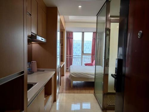 een keuken met een kamer met een bed en een raam bij Yangzhou Xianyun Apartment in Yangzhou
