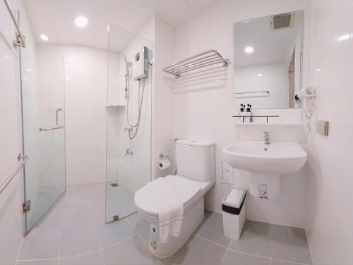 a white bathroom with a toilet and a sink at Nakara Hotel, Ubon Ratchathani in Ban Na Kham