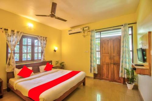a bedroom with a bed with red pillows and a window at Roseal Water Front in Baga