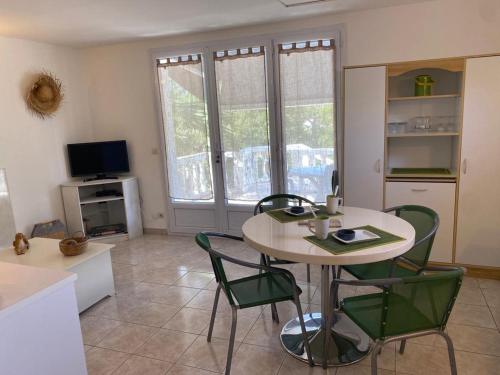 Una sala de estar con una mesa y sillas y un televisor. en Appartement T2 Olmeto, en Olmeto