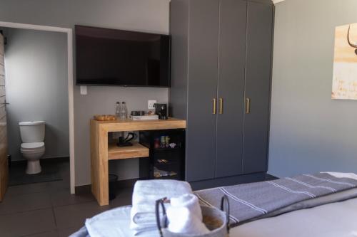 Schlafzimmer mit einem Bett, einem Schreibtisch und einem TV in der Unterkunft Waterfront Boutique Hotel Vanderkloof in Vanderkloof