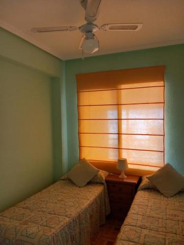 1 dormitorio con 2 camas y ventana en Apartamento Voramar Primera Linea de Mar, en El Campello