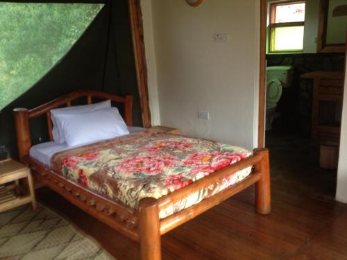 a bedroom with a bed with a floral comforter at Rushaga Gorilla Lodge in Bugambira