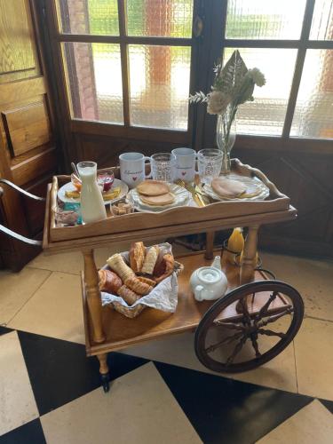 - une table avec du pain et des viennoiseries sur une voiturette dans l'établissement Suite romantique au château, à Moisdon-la-Rivière