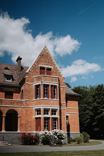 un vieux bâtiment en briques avec des fleurs devant lui dans l'établissement Suite romantique au château, à Moisdon-la-Rivière