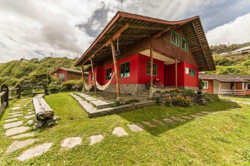 a red house with a green roof on a grass field at Hostería Miller FRENTE AL MAR in Bahía Mansa