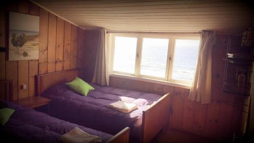 1 dormitorio con 2 camas y ventana en Hostería Miller FRENTE AL MAR, en Bahía Mansa