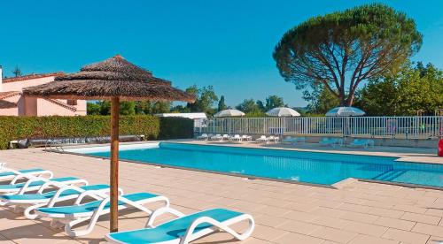 a group of chairs and an umbrella next to a swimming pool at camping Le Clos de la Lère in Cayriech
