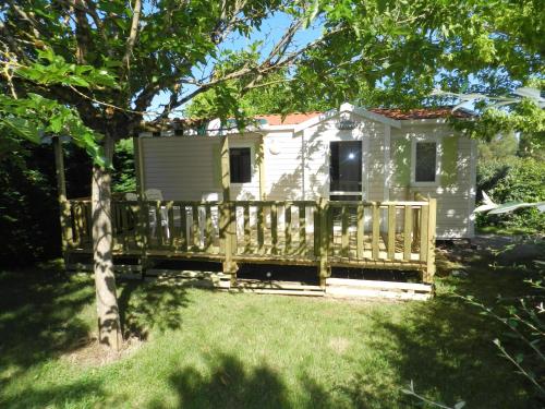 une petite maison avec une véranda et une clôture dans l'établissement camping Le Clos de la Lère, à Cayriech