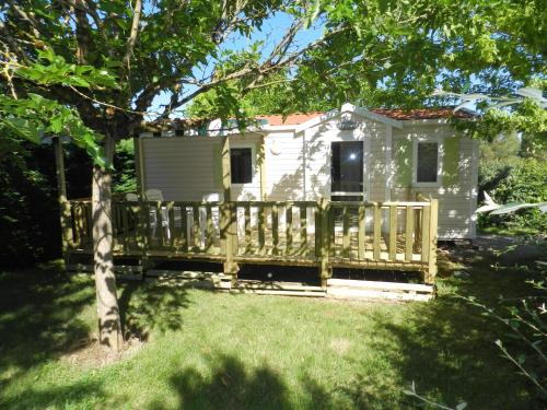 a tiny house with a porch and a fence at camping Le Clos de la Lère in Cayriech