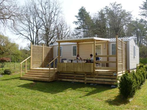 uma grande casa pequena de madeira com um alpendre em camping Le Clos de la Lère em Cayriech