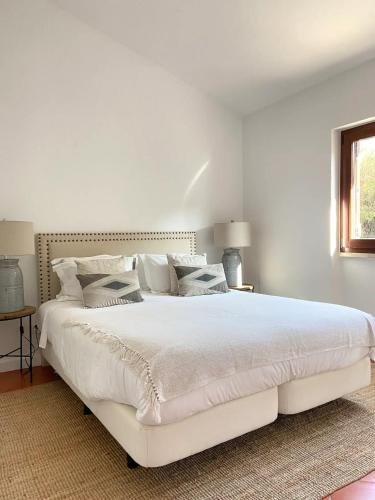 a white bedroom with a large white bed with pillows at Casa da Praia - Beachfront Private Pool in Colares