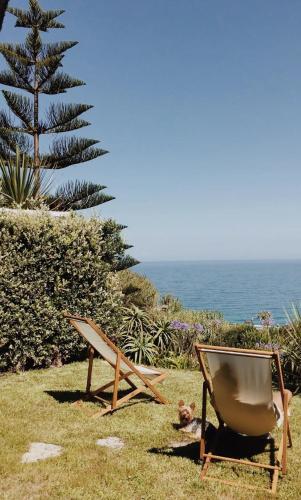 a chair sitting in the grass near the ocean at Casa da Praia - Beachfront Private Pool in Colares