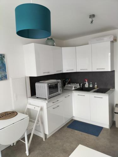 une cuisine avec des armoires blanches et un micro-ondes dans l'établissement Dormez au coeur du village entre plage et polder, à Barbâtre