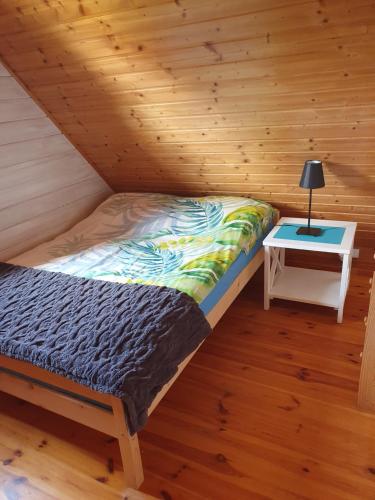 a bed in a wooden room with a table at Zagroda in Sarbinowo