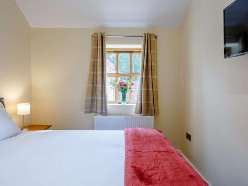 a bedroom with a bed and a window with a vase of flowers at 2 Bed in Bishop Auckland 83829 in Wolsingham