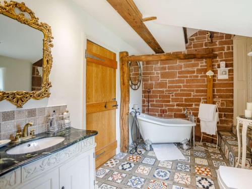 a bathroom with a tub and a sink and a brick wall at 1 Bed in Eden Valley 82493 in Kirkoswald