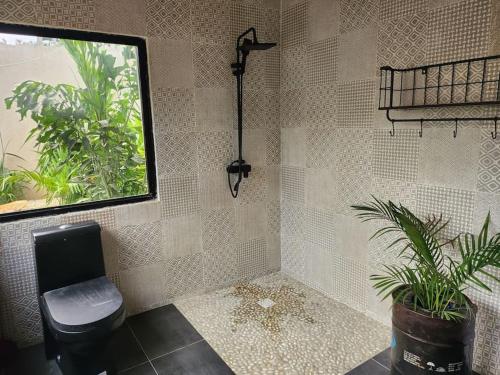 a bathroom with a toilet and a plant in it at Tiny Villa Votre Villa Privatisée in Ndangane
