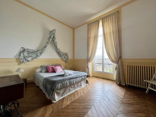 een slaapkamer met een bed en een groot raam bij Une nuit royale / Proche Forêt in Veneux-les-Sablons