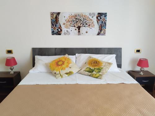 ein Schlafzimmer mit einem Bett mit zwei Kissen und einem Gemälde in der Unterkunft I GIRASOLI Short Rent in Palermo