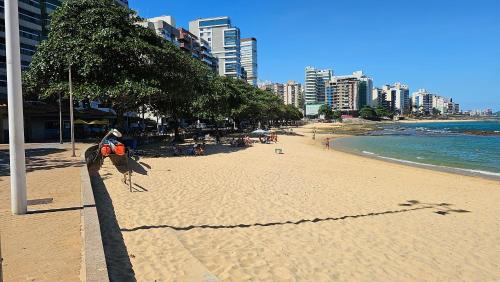 a sandy beach with people on the water and buildings at Apt em Edifício Frente a Praia Areia Preta in Guarapari