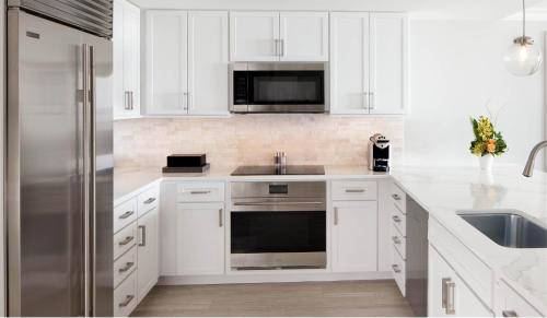 a kitchen with white cabinets and a stainless steel refrigerator at Sunseeker Resort Florida Gulf Coast, Curio Collection Hilton in Port Charlotte