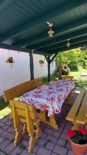 a table and benches under a pergola with a table and chairs at 100 Éves Vendégház - Háromhuta in Háromhuta