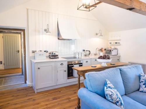 a living room with a blue couch and a kitchen at Grange Barn, Ashford In The Water in Great Longstone