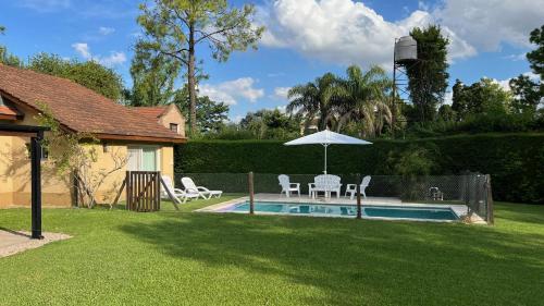 a backyard with a pool with chairs and an umbrella at Casa en Ing. Maschwitz con gran parque y pileta in Ingeniero Maschwitz