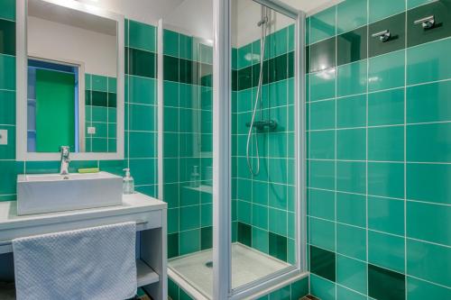 een groene betegelde badkamer met een douche en een wastafel bij Kergonano - Parking privé et piscine in Baden
