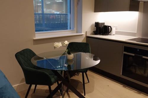a small kitchen with a glass table and two chairs at Soho super apartment in London